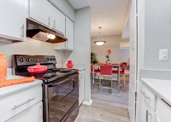 A kitchen with an oven and a stove and a dining room with a table